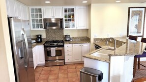 A compact kitchen with white cabinetry, stainless steel appliances, and a granite countertop. - Walking distance from the World Famous, Indian Wells Tennis Gardens (La Quinta)