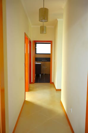 A hallway leading to a kitchen with a window, a door, and a light fixture. - Sunset Villa Madeira (Ribeira Brava)