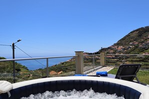 A hot tub with a clear view of a coastal town and the sea. - Sunset Villa Madeira (Ribeira Brava)