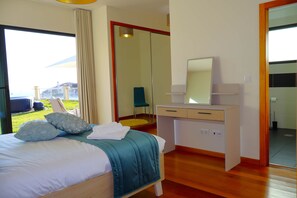 Ein Hotelzimmer mit Bett, Schreibtisch, Spiegel und Blick ins Freie.