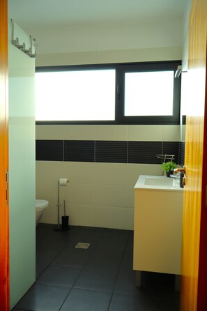 A bathroom with a toilet, sink, and window. - Sunset Villa Madeira (Ribeira Brava)