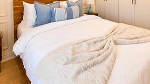 A bedroom with a large bed, a nightstand, a lamp, and a wardrobe.