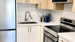 A modern kitchen with stainless steel appliances, wooden cabinets, and a granite countertop.