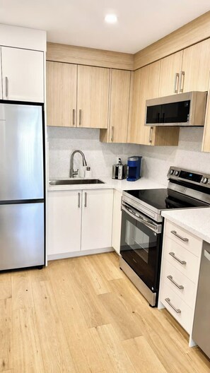 A modern kitchen with stainless steel appliances, wooden cabinets, and a granite countertop.