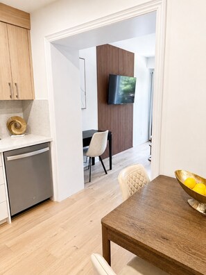 A modern kitchen with wooden cabinets, a dishwasher, and a dining area with a table and chairs.