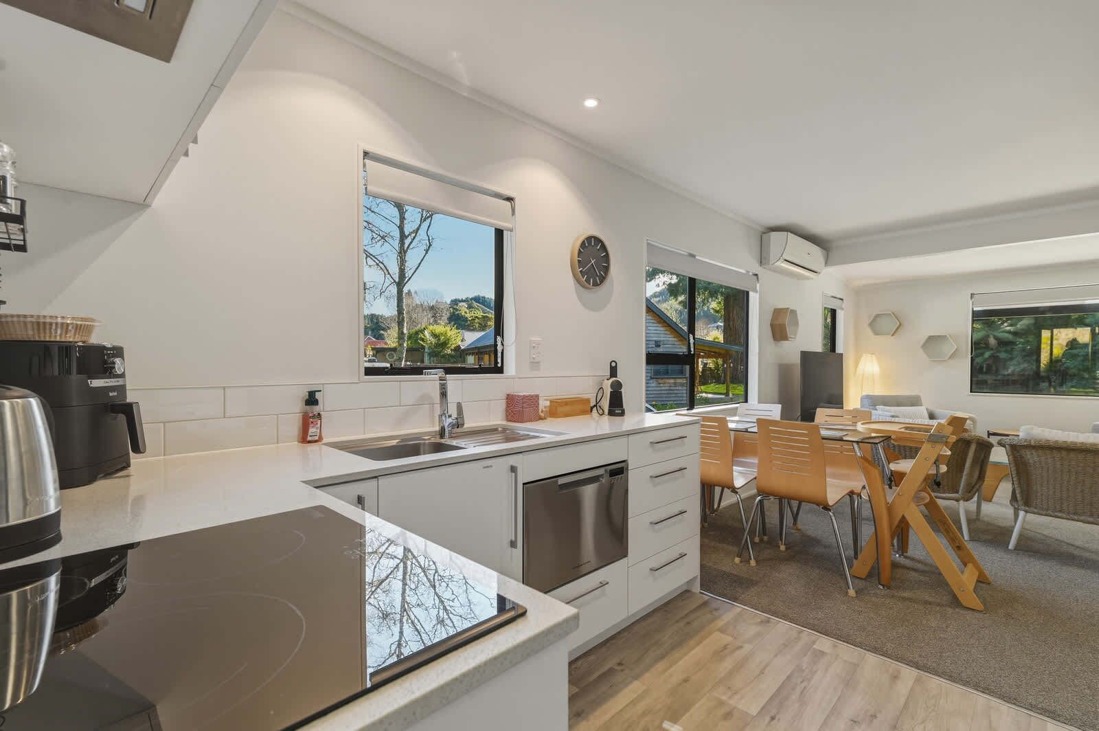 A modern kitchen with a built-in stove, a sink, and a dining area with a table and chairs.