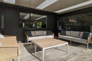 An outdoor patio with a sofa, chairs, and a table. - Amalia Cottage - Lake Okareka, Huge Covered Deck, Sleeps 4 (Rotorua)