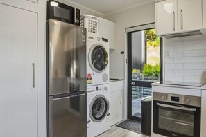 Eine moderne Küche mit einem Edelstahl-Kühlschrank, einer Bosch Waschmaschine und einem Samsung Backofen.