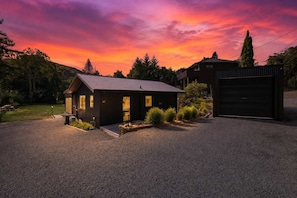 A modern house with a gravel driveway, a garage, and a well-maintained garden. - Amalia Cottage - Lake Okareka, Huge Covered Deck, Sleeps 4 (Rotorua)