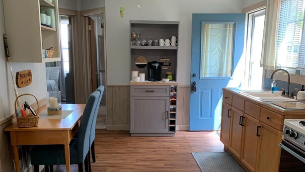 Una cocina compacta con comedor, piso de madera y una puerta azul.