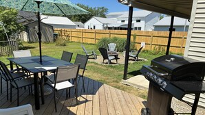 Una terraza con una parrilla, sillas y una mesa.