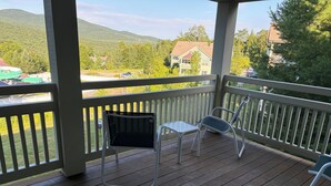 A wooden deck with white railings, two chairs, and a table. - SMUGGLERS NOTCH. Ski in/ski out. Popular  ski retreat.Stay onsiteSki Lift access (Jeffersonville)