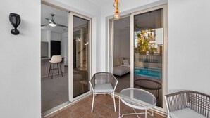 Ein Zimmer mit einer Schiebetür zum Balkon, einem Deckenventilator und einer Pendelleuchte.