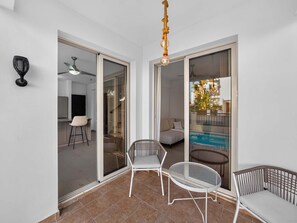 Ein Zimmer mit einer Schiebetür zum Balkon, einem Deckenventilator und einer Pendelleuchte.