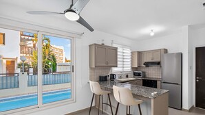 Eine moderne Küche mit integrierter Kochinsel, Barhocker, einem Kühlschrank und einem Deckenventilator.