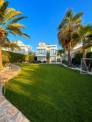 A well-maintained lawn with a modern building in the background. - Luxury Seafront Villa | Private Beach, Pool&Garden (Oroklini)