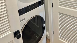 Vista frontal de uma máquina de lavar e secar empilhadas, com painel de controle e puxador.