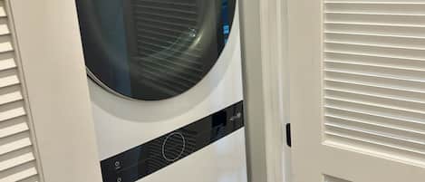 A front view of a stacked washer and dryer unit with a control panel and a door handle.