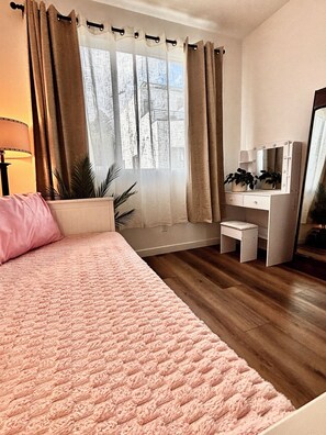A bedroom with a bed, a desk with a mirror, a window with curtains, and a plant. - New Bedroom + Rooftop by DTLA, Dodgers, Universal, Griffith Park (Los Angeles)