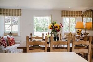 A dining area with a wooden table set for four, surrounded by wooden chairs.
