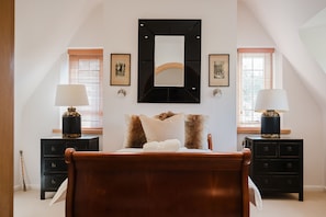 A bedroom with a bed, two nightstands, a mirror, and framed pictures on the wall.