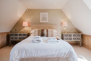 Ein Schlafzimmer mit einem großen Bett, zwei Nachttischen, einer Kopfteil und einem gerahmten Bild an der Wand.