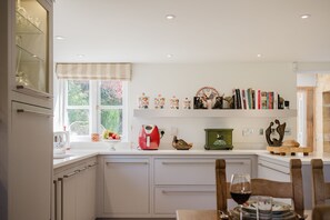 A modern kitchen with white cabinetry, a red kettle, and a variety of decorative items on the wall.