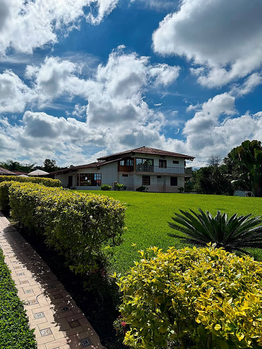 A two-story building with a tiled roof, surrounded by well-maintained lawns and hedges.