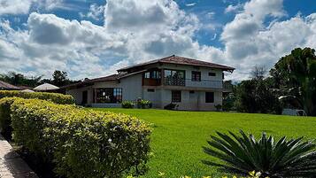 A two-story building with a tiled roof, surrounded by well-maintained lawns and hedges.
