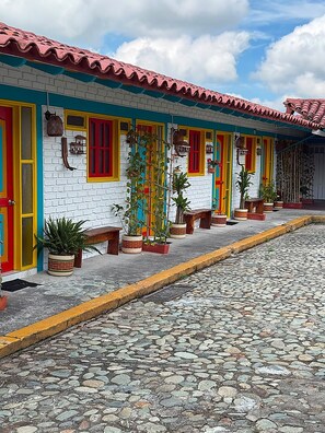 Un edificio con techo de tejas rojas y fachada de ladrillo blanco, con puertas y ventanas de colores.