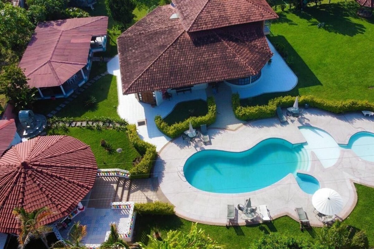 Una propiedad residencial con piscina, varios sombrillas y un césped bien cuidado.
