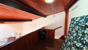 Eine Holztreppe mit Handlauf, einer Deckenleuchte und einer Wand mit einem Blumenmuster.
