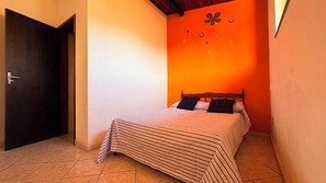 A room with a bed, a door, and a wall with a butterfly and raindrop decoration. - Cozy house in Itagua (Ubatuba)