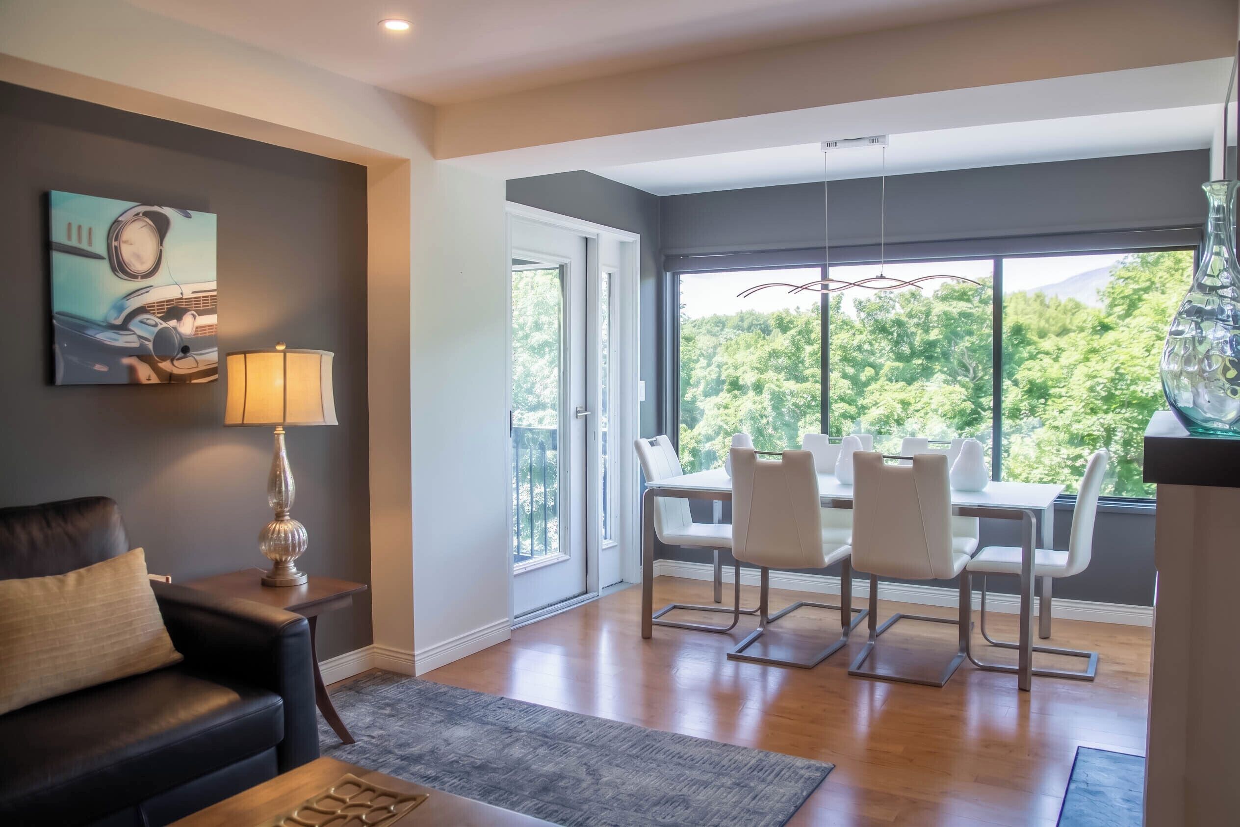 A modern living room with a sofa, a table, and chairs, a lamp, and a painting on the wall.