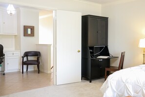 A hotel room with a bed, a desk with a chair, a wardrobe, and a door leading to another room. - 3-BD/2.5-BA Charming Getaway, Only 10 mins to DT! (Houston)