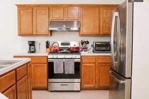 A kitchen with wooden cabinets, a stainless steel refrigerator, a stove, and a microwave. - 3-BD/2.5-BA Charming Getaway, Only 10 mins to DT! (Houston)