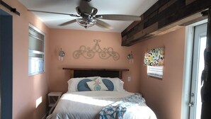 A bedroom with a bed, a ceiling fan, a window with blinds, and a door. - Cozy cottage in charming St. Cloud perfect for your getaway. (St. Cloud)