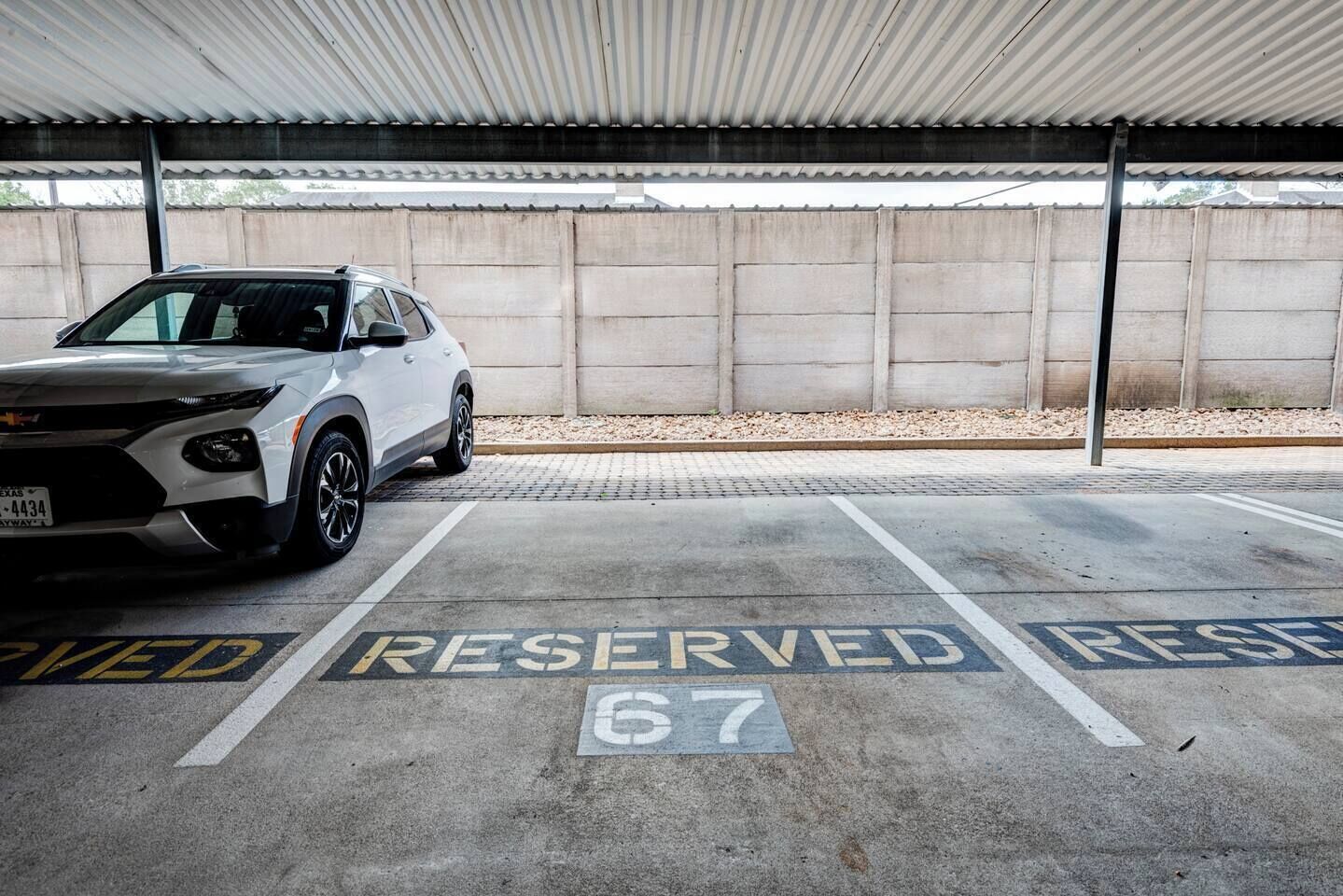 A parking area with a white SUV parked in a reserved space marked with the number 67.