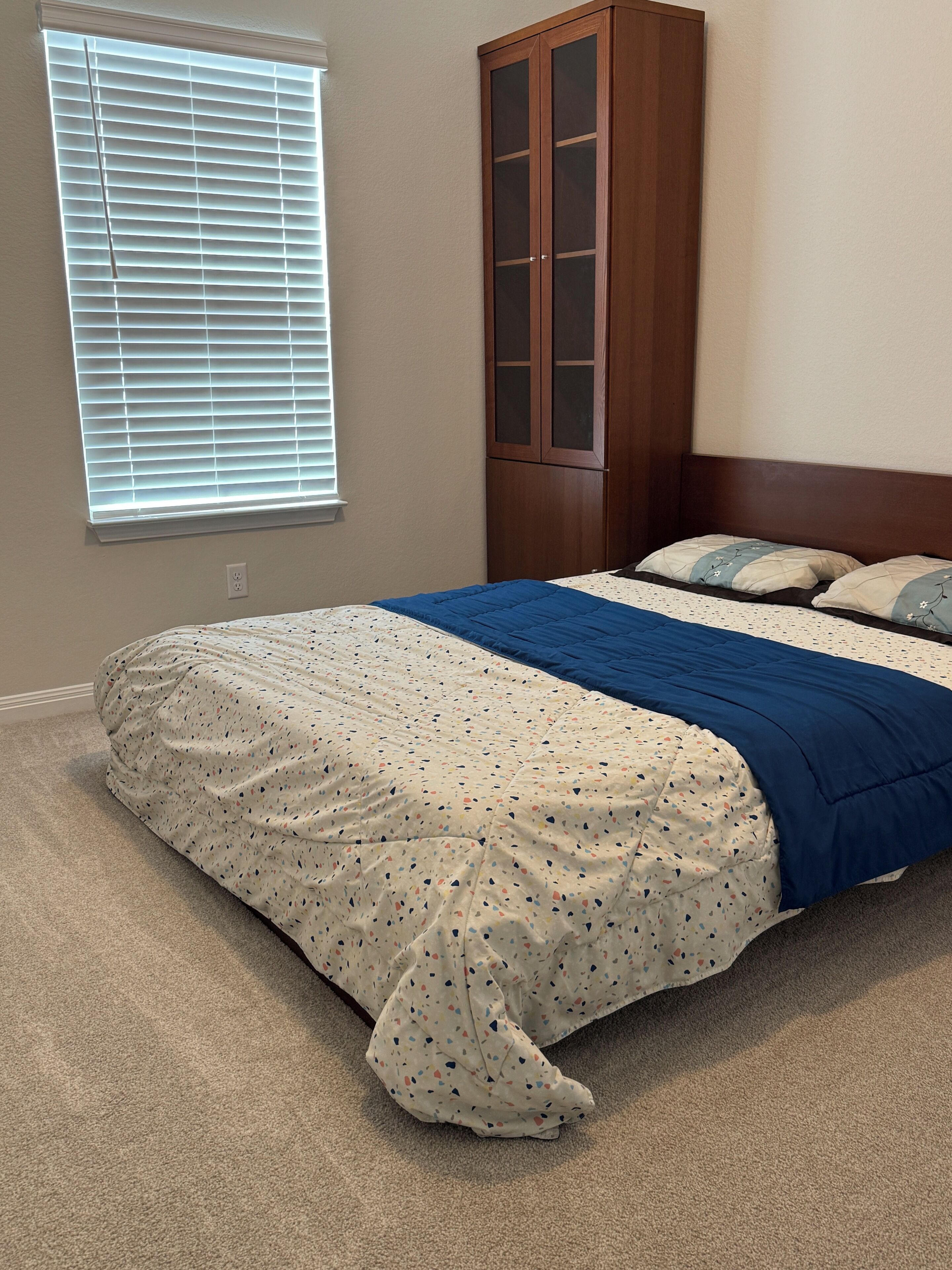 Ein Schlafzimmer mit einem Bett, einem Kleiderschrank und einem Fenster mit Jalousien.