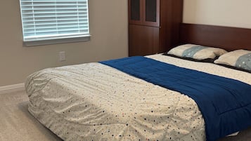 Ein Schlafzimmer mit einem Bett, einem Kleiderschrank und einem Fenster mit Jalousien.