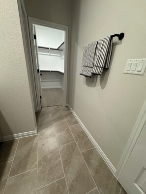 A hallway with a door leading to a closet, a towel rack with a striped towel, and a light switch on the wall. - Modern Georgetown Escape - A brand-new home base in the heart of Georgetown (Georgetown)