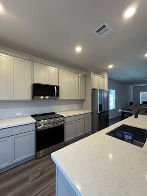 A modern kitchen with white cabinetry, stainless steel appliances, and a marble countertop. - Modern Georgetown Escape - A brand-new home base in the heart of Georgetown (Georgetown)