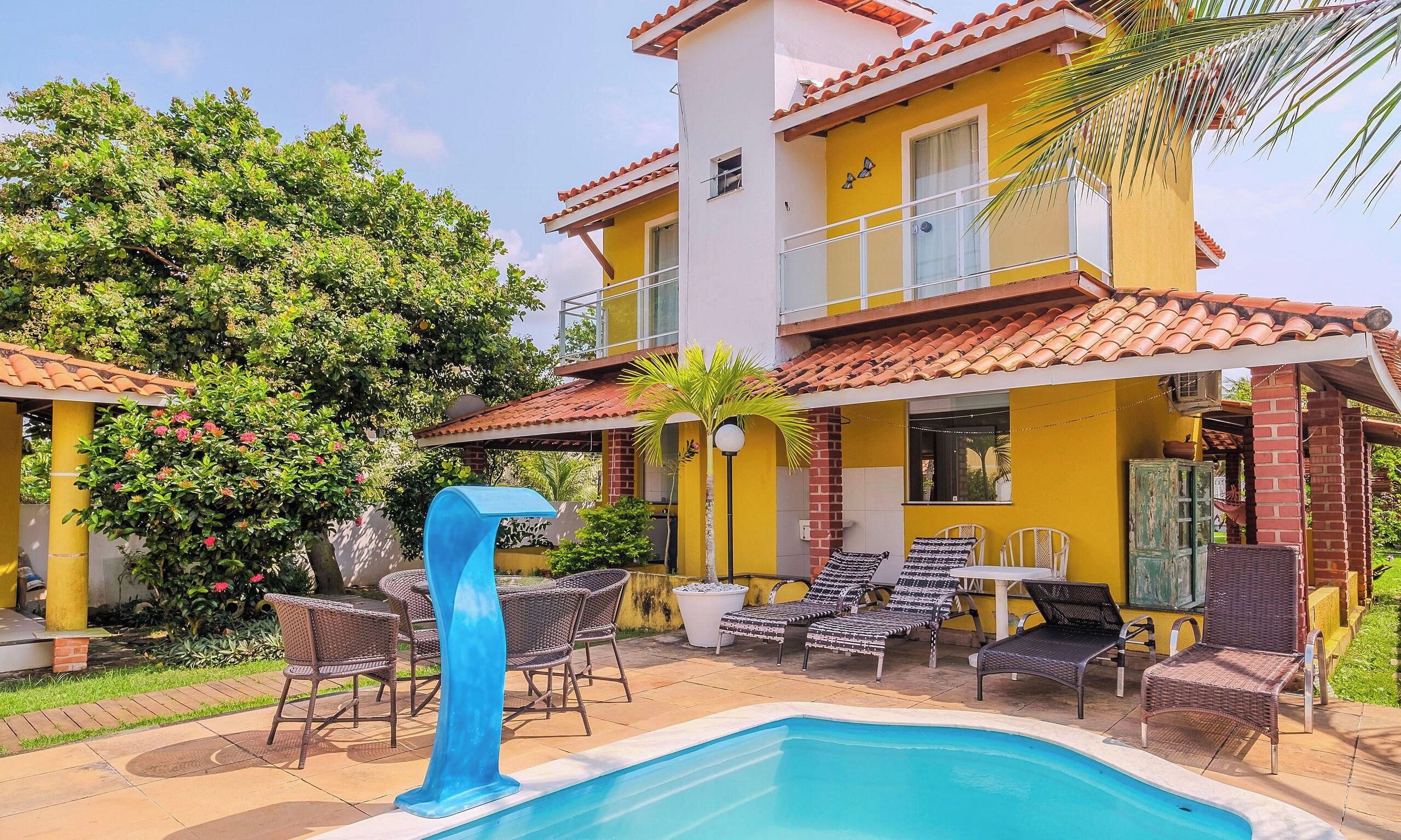 A two-story building with a swimming pool, outdoor seating, and a balcony.