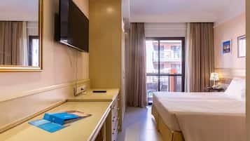 Ein Hotelzimmer mit einem Bett, einem Schreibtisch, einem Flachbildfernseher, einem Spiegel und einem Fenster mit Vorhängen.