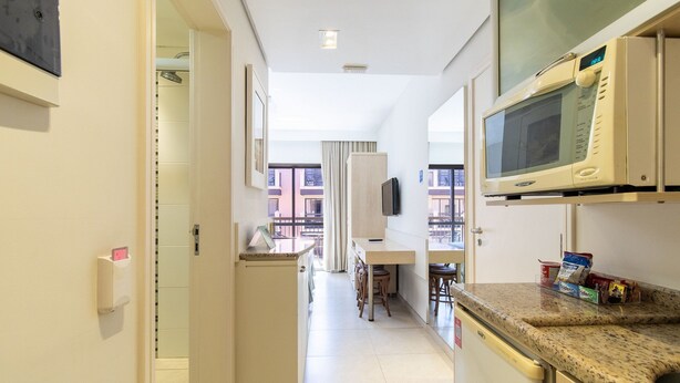 Uma cozinha compacta com micro-ondas, um pequeno espaço de refeições e vista para o exterior.