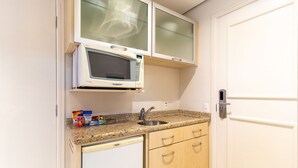 Uma cozinha compacta com micro-ondas, pia e um pequeno balcão com lanches.