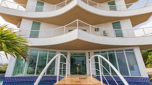 Et hotel med flere etager, en buet facade, balkoner og et poolområde.