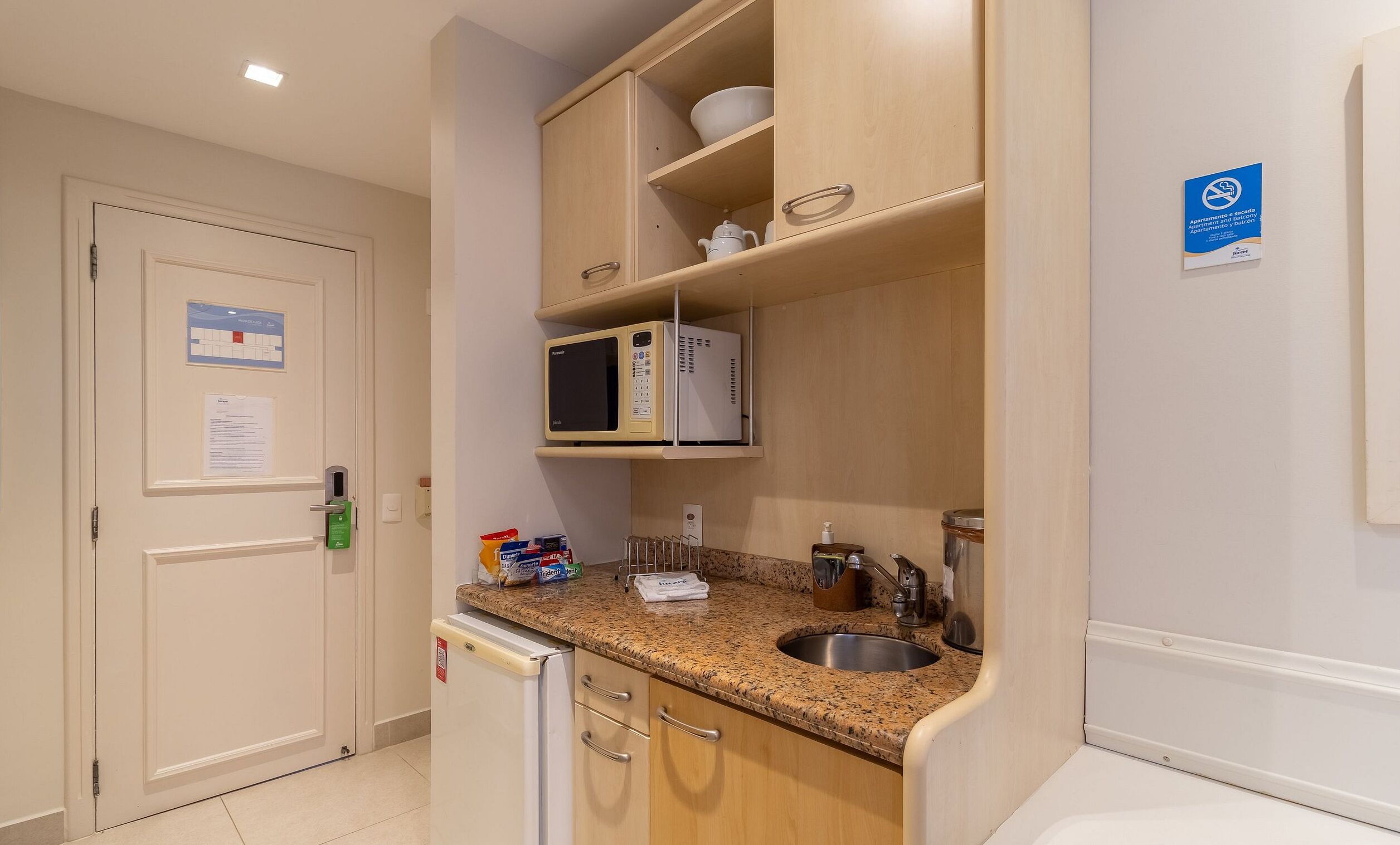 A compact kitchenette with a microwave, sink, and storage cabinets.