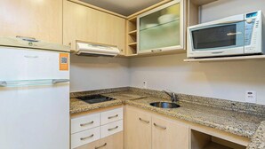 A compact kitchen with a built-in microwave, a refrigerator, and a granite countertop. - Apt W/pool in Luxury Resort in Jurere Jbv167 (Florianópolis)