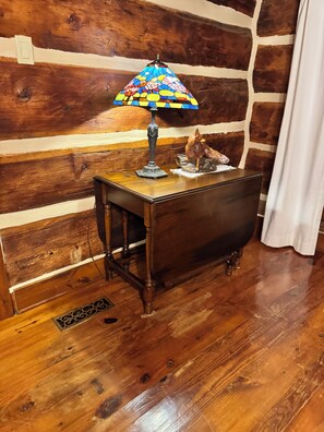 A wooden table with a stained glass lamp and a wooden sculpture.